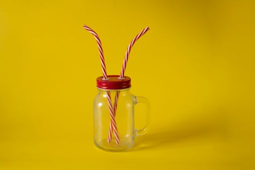 A closeup shot of two straws in a cup isolated on a yellow background