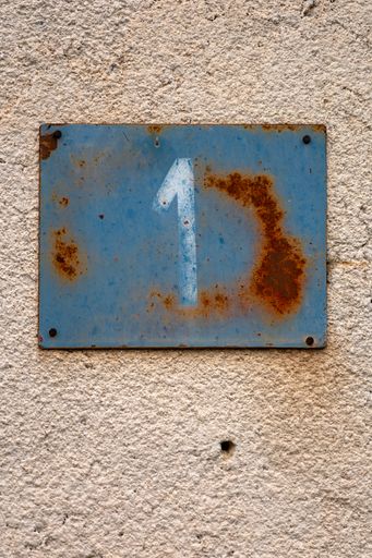 A vertical shot of a sign on the wall with a building number ''one''