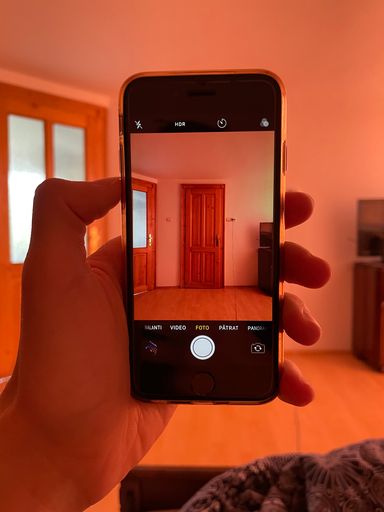 A closeup shot of a hand taking a photo of a bedroom's door with a phone