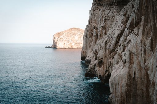 The beautiful Mediterranean sea surrounded by rocky cliffs under a blue sky on a sunny day in Sardinia