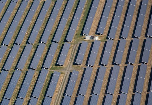 An aerial view of rows of solar panels on a field