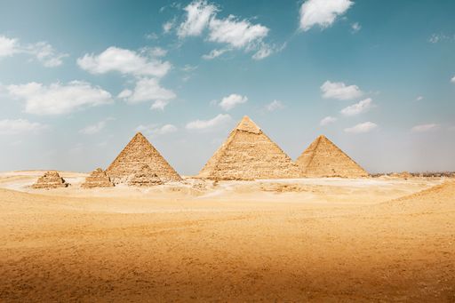 The iconic pyramids of Giza under a clear blue sky, showcasing ancient architecture in the Egyptian desert.