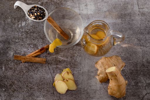 preparation of a ginger and cinnamon infusion with fresh produce natural roots and cinnamon stick served in a pitcher and a cup