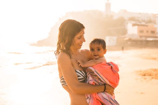 A young Spanish mother with her baby on a beach at sunset, Morro Jable, Pajara, Fuerteventura, Spain