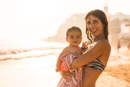 A smiling mother with her six-month-old baby at sunset on a beach, Morro Jable, Municipality of Pajara south of Fuerteventura, Canary Islands, Spain