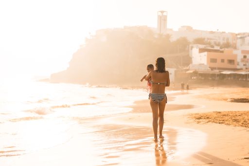 A young Spanish mother with her baby on a beach at sunset, Morro Jable, Pajara, Fuerteventura, Spain