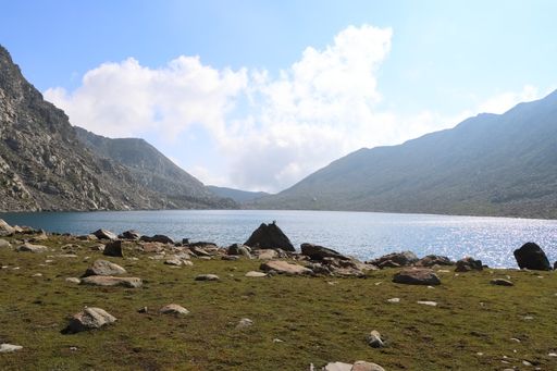 A shot of a lake with fields and stones near the Himalayas in Jammu, Kashmir, India