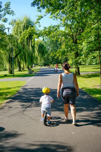 A woman and her child on a small bike on a footpath in the Jan Pawla park