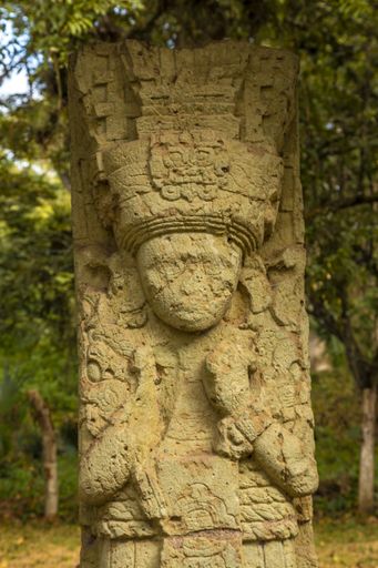 A vertical shot of a statue carved on a stone in Honduras Mayan ruins