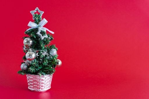 A Christmas tree with silver ornaments isolated on a red background with a copy space