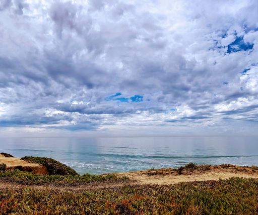 A beautiful clean ocean with calm waves under a blue sky with fluffy clouds during the daytime