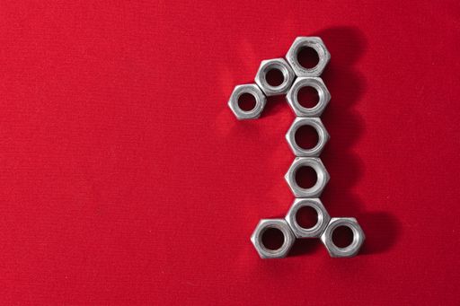 A number one, made with steel nuts on red fabric background