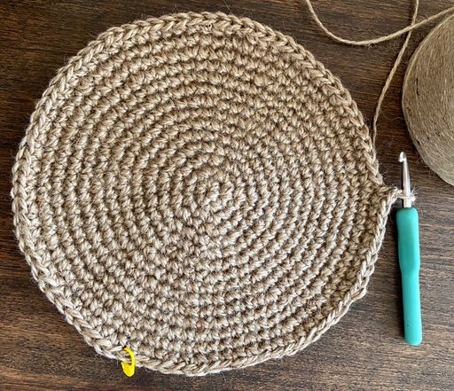 Weaving a jute table mat; round placemat on the wooden table