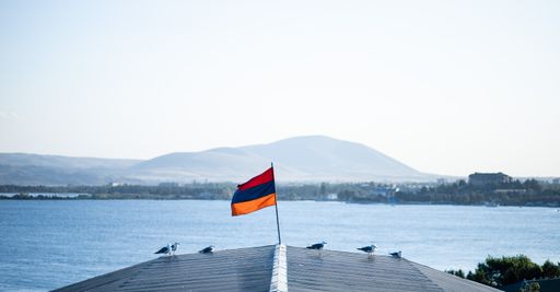 A group of gulls perched on a roof with an Armenian flag on the bay of Lake Sevan in Armenia