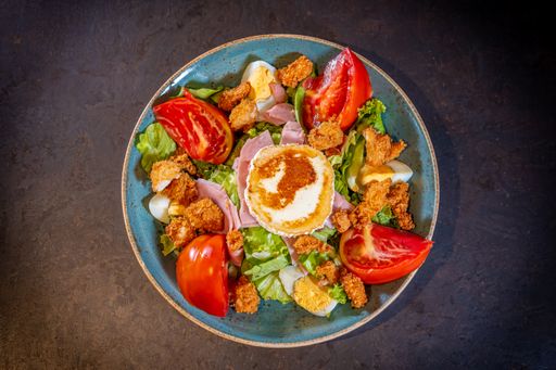 A top view of a delicious salad with ham, cheese, and chicken on a black background