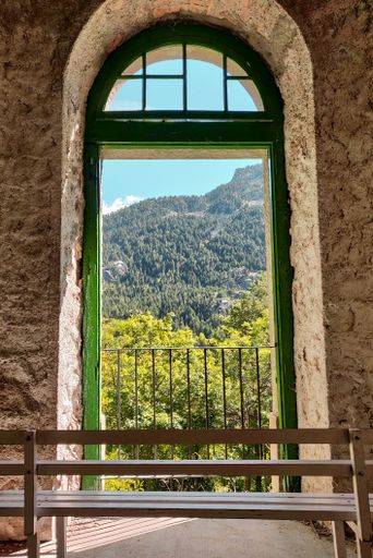 Beautiful shot of a bench with a mountain view through a balcony during daytime in Panticosa in the Pyrenees
