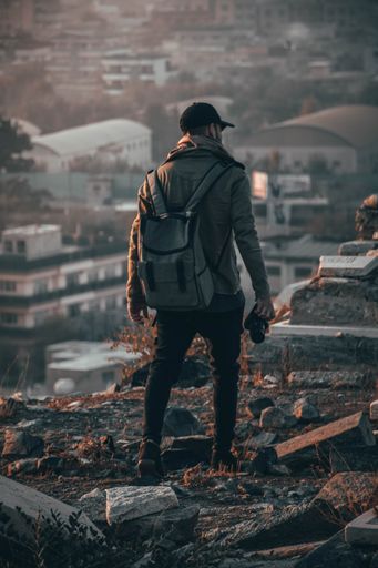 A male photographer walking on ruins of old stone architecture in the mountains
