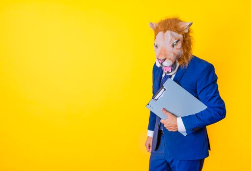 Unrecognizable businessman with lion mask holding a folder with hand. Yellow background with copy space.