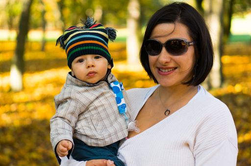 A happy mother resting in the autumn park with her little son