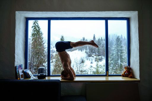 A Caucasian man doing yoga on a windowsill