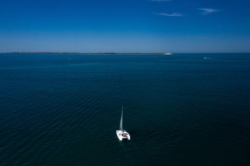 A solitary sailboat on a vast blue ocean under a clear sky, capturing the essence of tranquility and freedom.