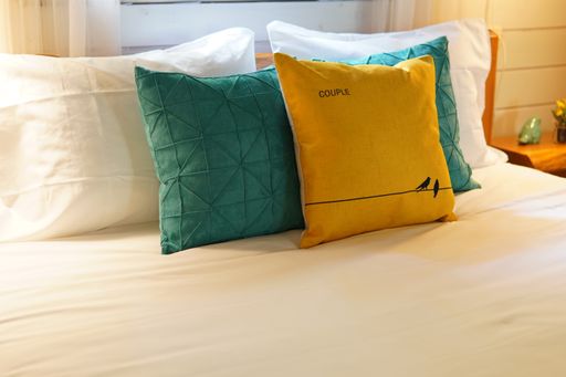 The yellow and green pillows on the couch in the room with electric light in it