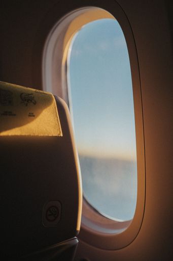 View from an airplane window with warm sunlight illuminating the seat, creating a serene travel atmosphere.