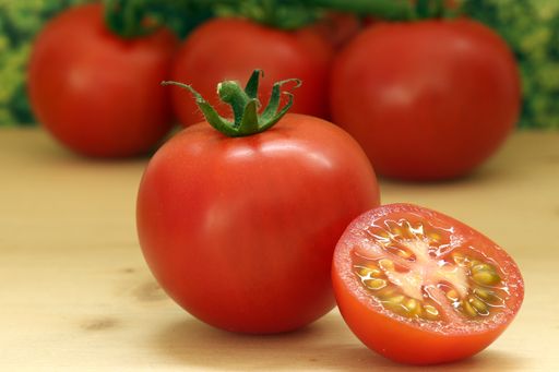 A selective focus shot of red tomatoes  on a brown wooden surface