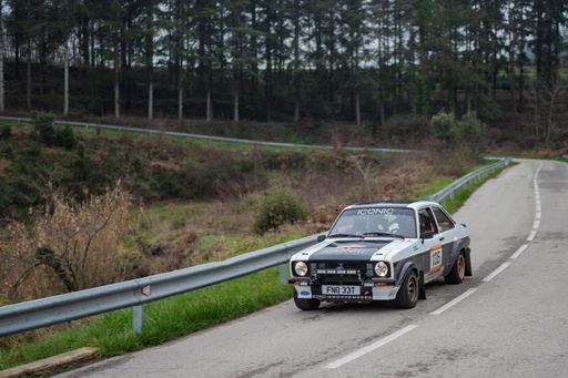 Ford Escort RS1800 competing in the 73rd Rally Costa Brava, driven by Nick Whale and Ian Windress, speeding through a winding forest road