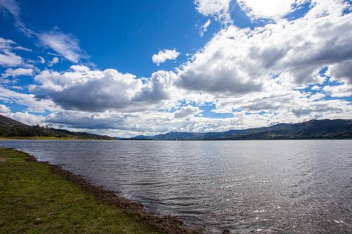A landscape view of a beautiful clean lake under a blue cloudy sky on a sunny day