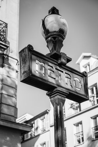 A grayscale low angle shot of a Metro sign in Metro Station, Paris, France