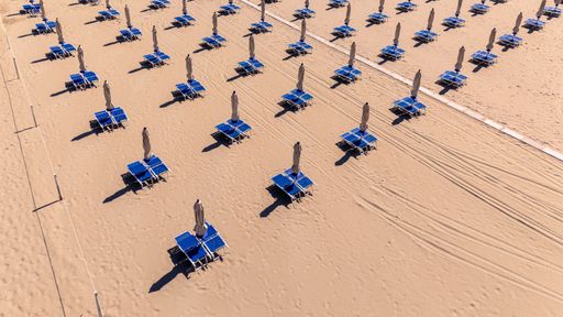 Sun loungers and umbrellas set up on an Italian beach in early June 2025, awaiting the start of the summer season.