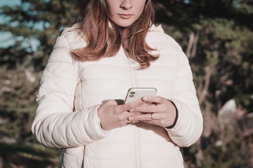 Young Latina woman using her cell phone in a park setting.