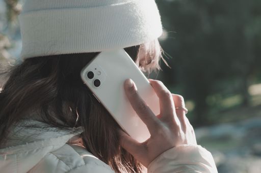 Young woman wearing a beanie talking on a smartphone in an outdoor setting, showcasing modern communication.