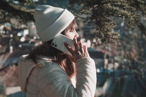 Young Latina woman using her phone in the park, wearing headphones.