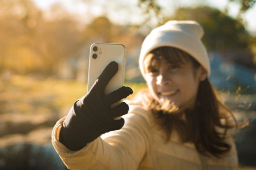 Young Latina woman taking a selfie with her cell phone in the park