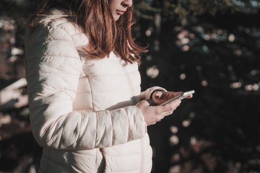 Young Latina woman using her cell phone in the park on a sunny day.