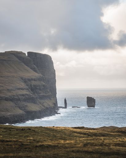 Steep cliffs of Faroe Islands. Vertical cliffs. Massive rocky cliffs, Breathtaking northern landscape, North Atlantic Ocean. Views of Eysturoy Island
