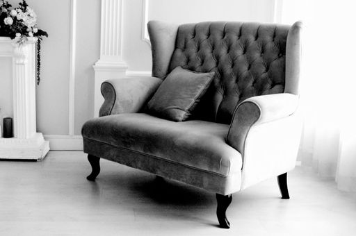 A black and white shot of a cushiony sofa with a pillow in the sitting room