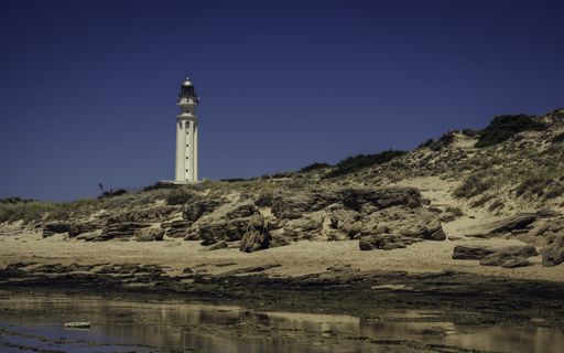 A beautiful shot of a lighthouse on a seashore with a clear blue sky in the background
