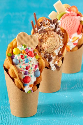 A closeup shot of bubble waffle ice cream in paper packages on a blue background