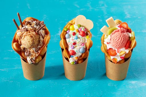 A closeup shot of bubble waffle ice cream in paper packages on a blue background