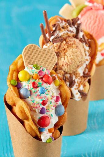 A closeup shot of bubble waffle ice cream in paper packages on a blue background