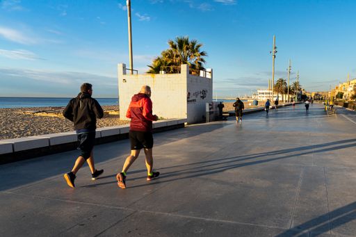 A closeup shot of people jogging near the sea on a sunny day