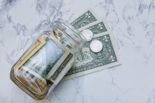 A high angle view of dollars and coins in a jar on the table under the lights - money concept