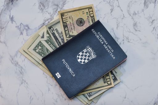 A high angle view of a Croatian Passport on dollars on the table under the lights - money concept