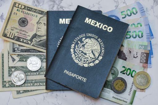A high angle view of two Mexican Passports on dollars and pesos on the table under the lights