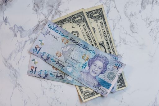 A high angle view of Cayman Islands dollars and US dollars on the table under the lights