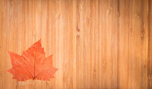 The bright orange autumn leaf on the wooden surface viewed from above