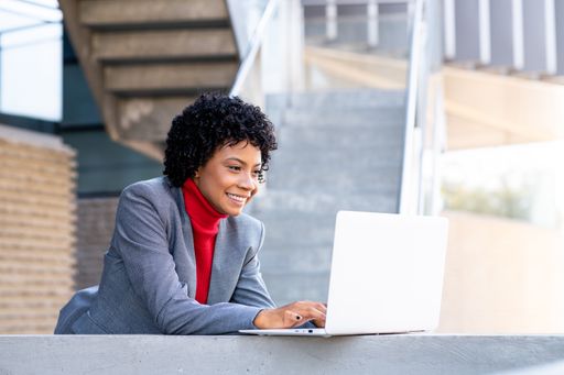 A young African-American businesswoman using her phone and laptop in a business building